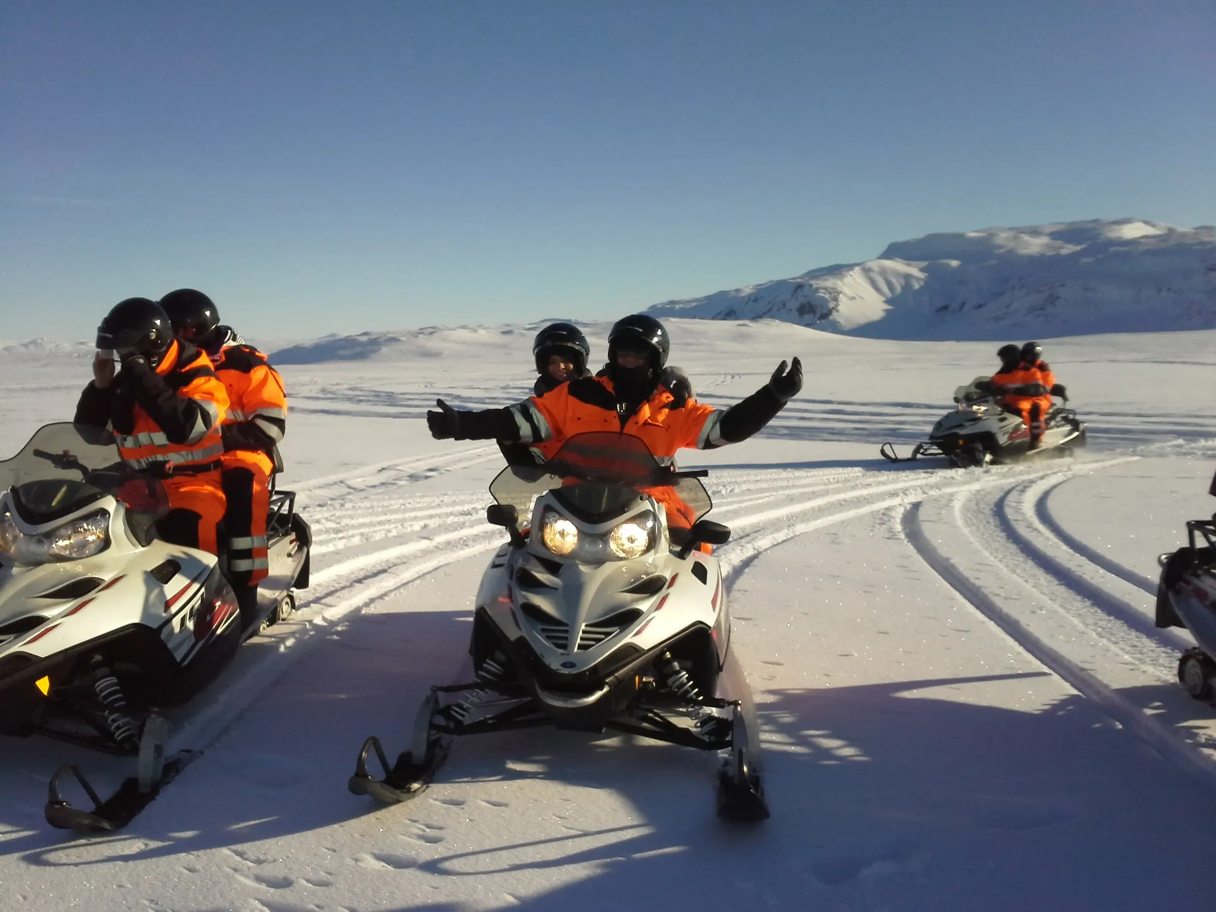 Group on snowmobiles waving on the glacier