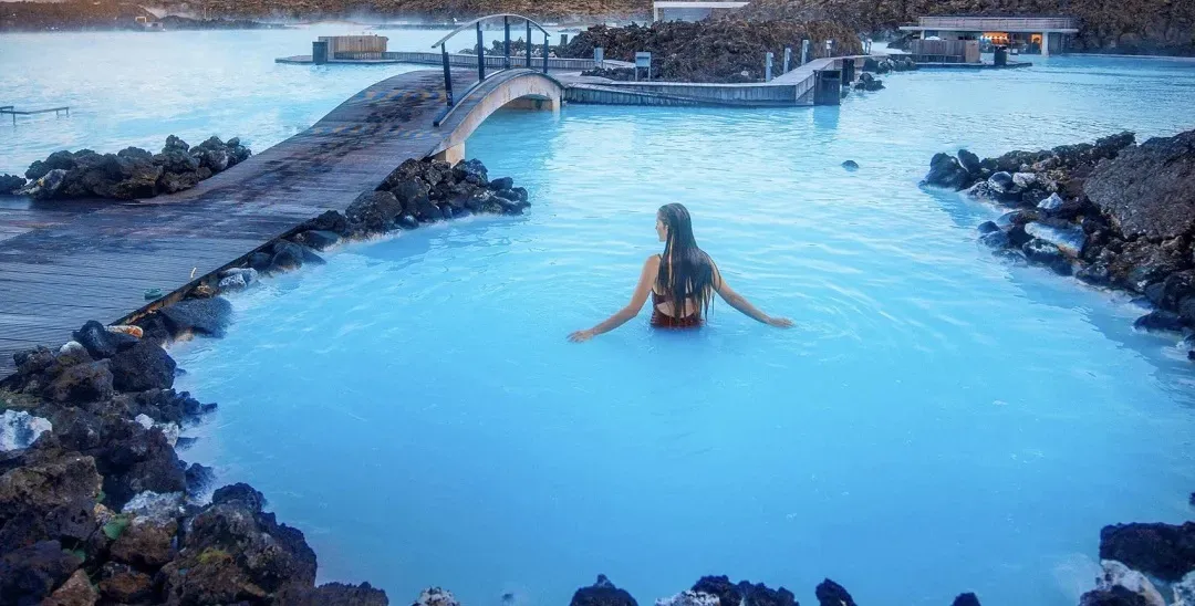 Woman wading through the milky-blue water of the Blue Lagoon