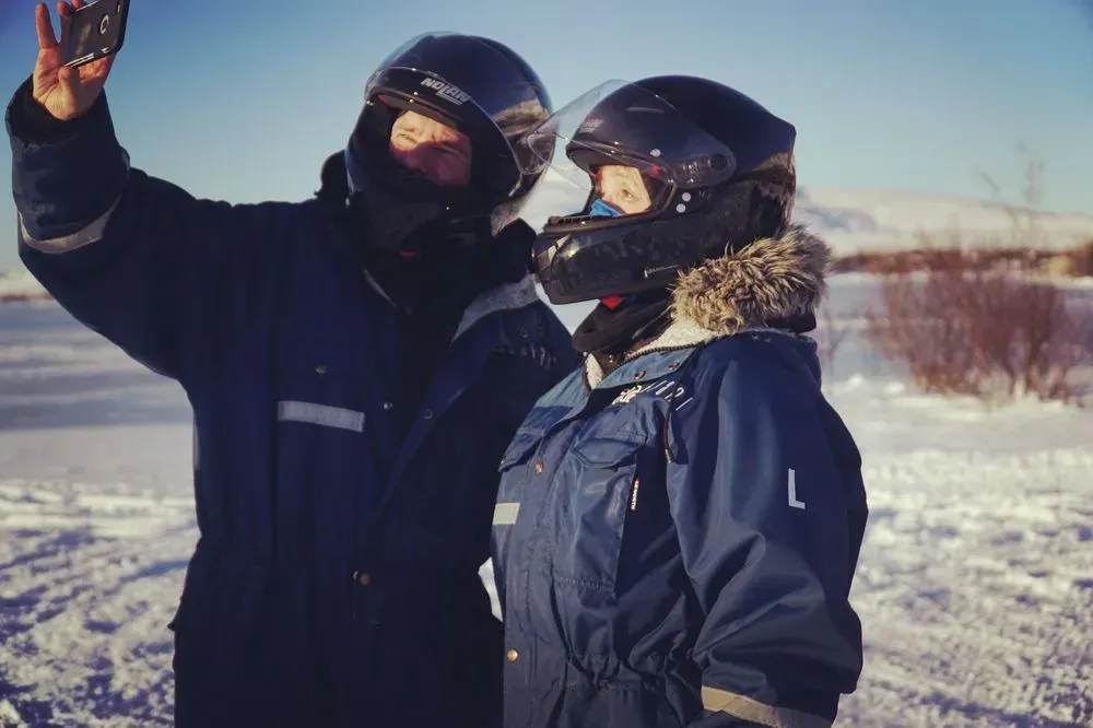 Two riders in helmets taking a selfie in the snow