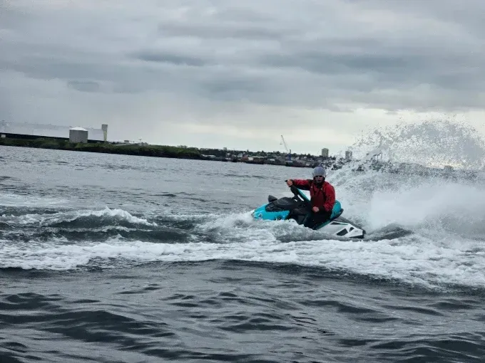 Rider in a red drysuit speeding across Reykjavík Bay on a jet ski