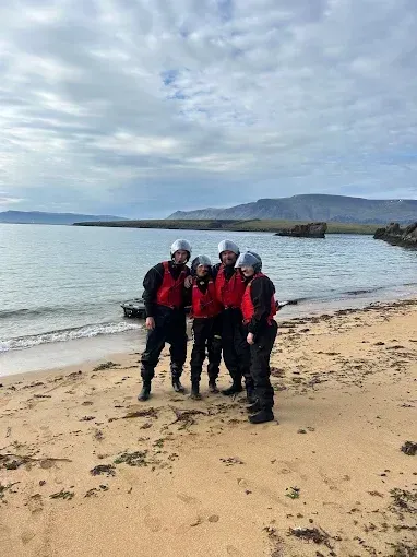 Group in red drysuits on a beach after a jet ski tour