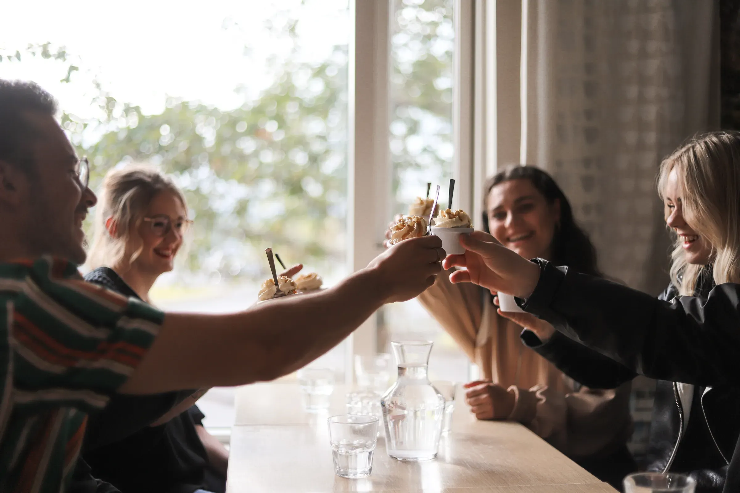 Friends toasting with desserts at a café table